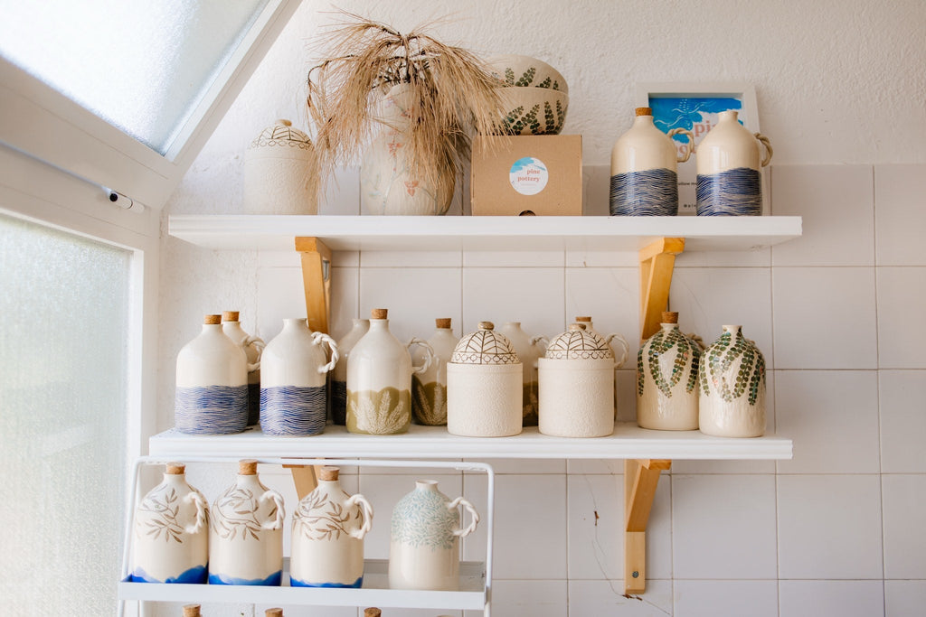 Shelves in a ceramics studio in Split with handmade olive oil bottles decorated with sea, olive and pine motifs