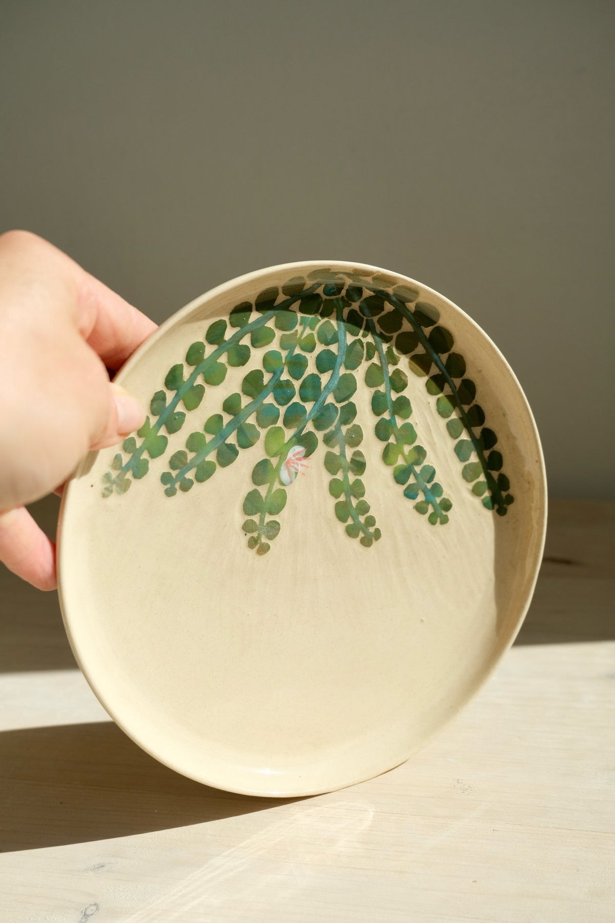 Capers plate – handmade stoneware plate with green caper leaf sgraffito, held in hand